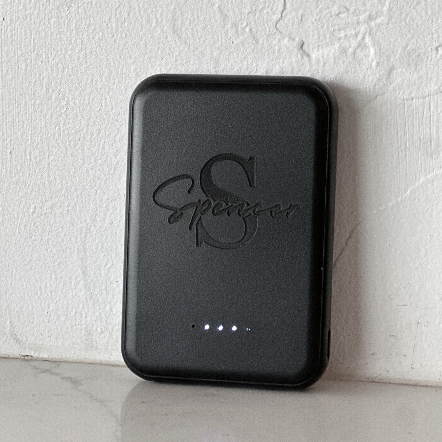 Black magnetic portable charger fits easily in the palm of the hand, emphasizing its slim, travel-ready design. Fast-charging power bank is perfect for teachers, seniors, college students, business professionals, or as a personalized wedding party gift.