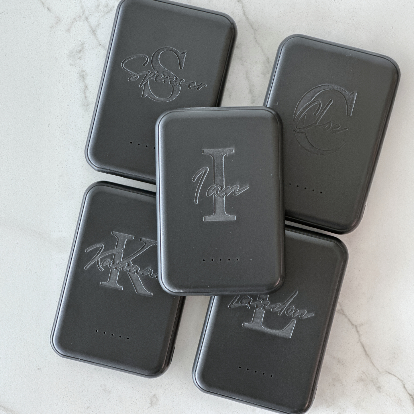 Close-up of sleek black magnetic power bank attached to the back of a phone, demonstrating hands-free wireless charging. A perfect everyday tech essential and thoughtful gift for groomsmen, bridesmaids, teachers, employees, or corporate giveaways.