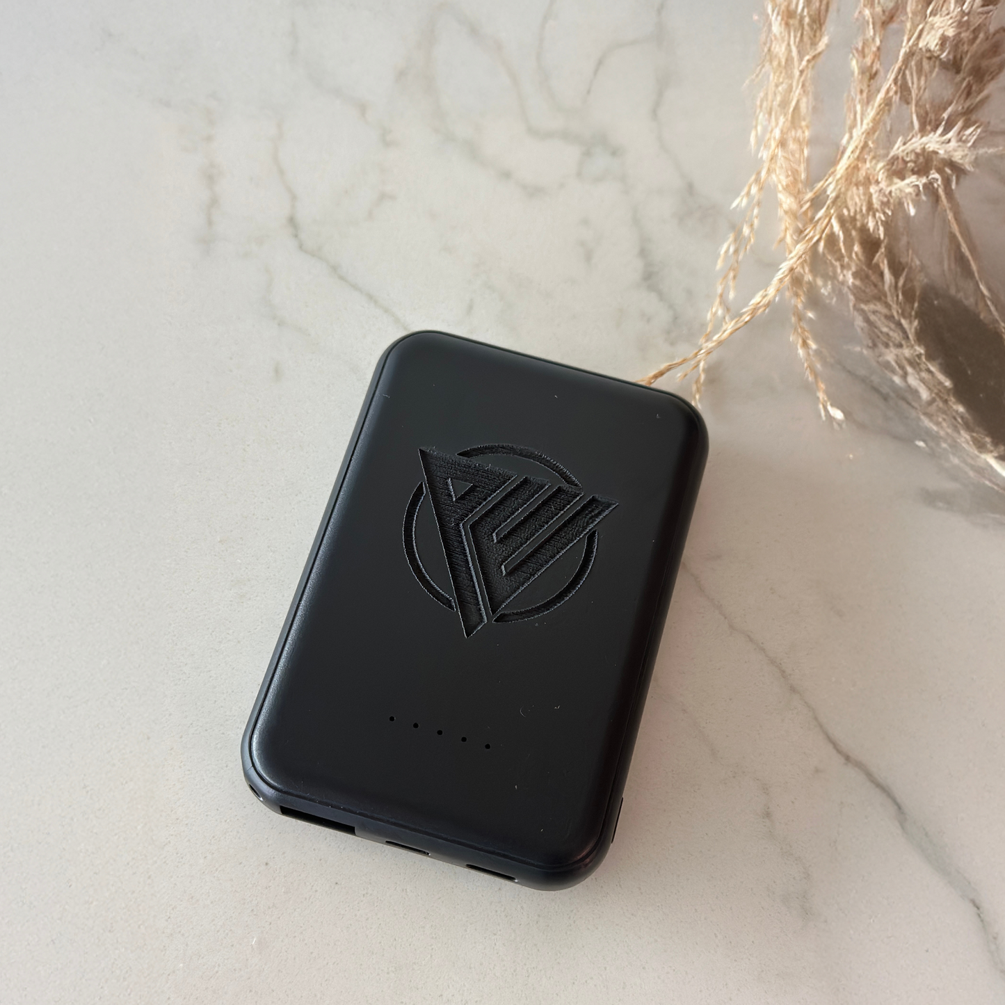 Modern black magnetic portable charger displayed on a desk beside office supplies, highlighting its professional look. Compact power bank is great for travel, employee gifts, teacher appreciation, senior-friendly charging, or wedding party gifts.