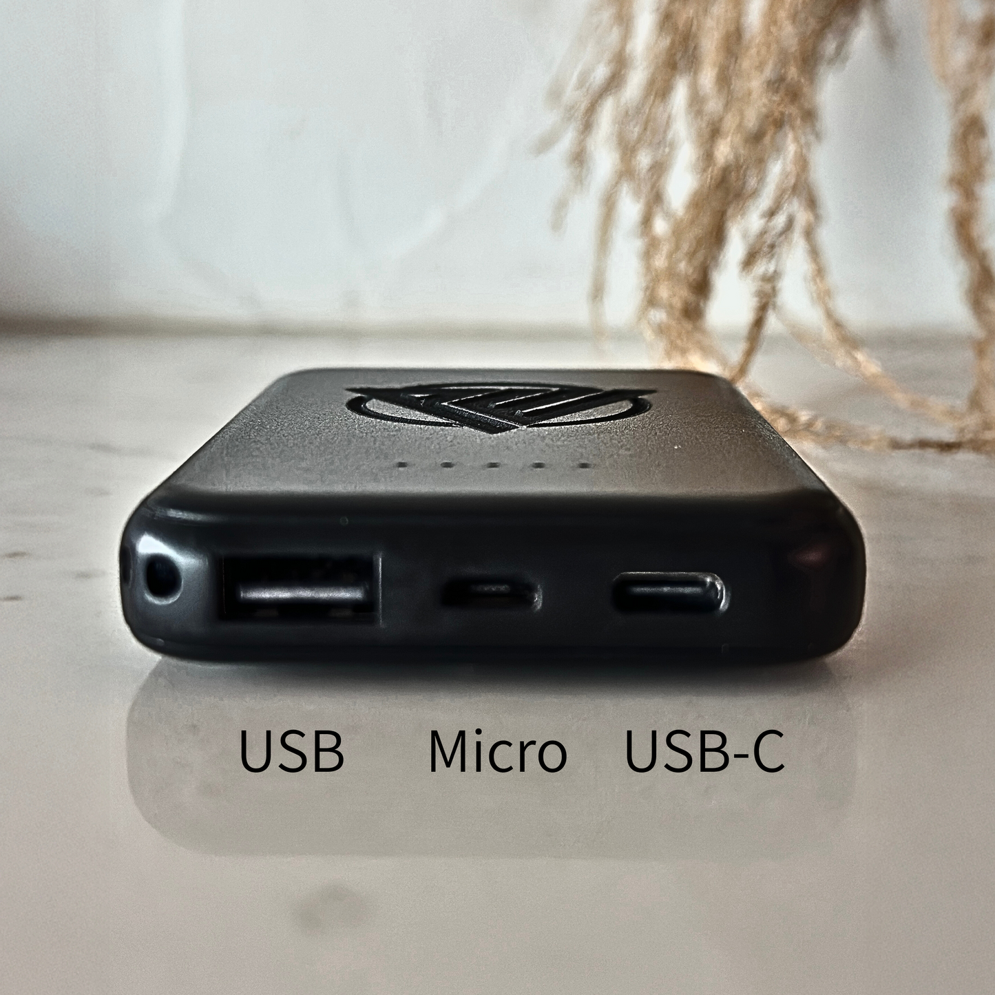 Close-up of sleek black magnetic power bank attached to the back of a phone, demonstrating hands-free wireless charging. A perfect everyday tech essential and thoughtful gift for groomsmen, bridesmaids, teachers, employees, or corporate giveaways.